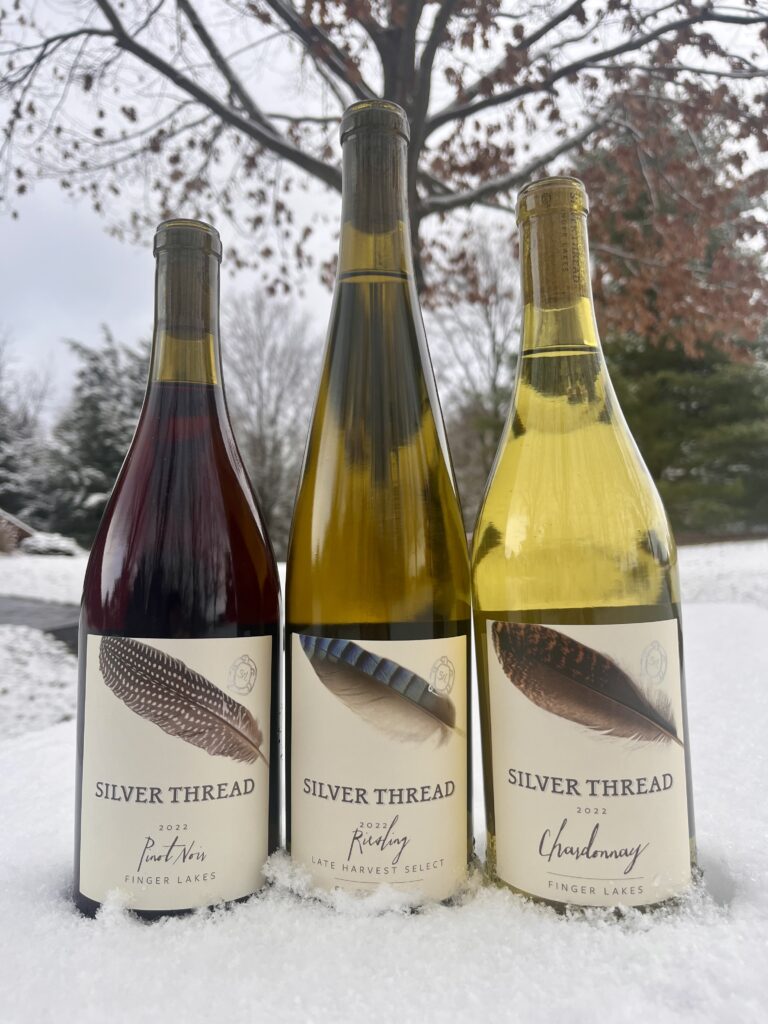 Three bottles of 2022 wines in the snow.