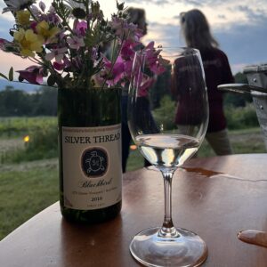 Wine glass with wildflowers outside on a table.