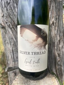 A bottle of Good Earth White Wine against a tree.