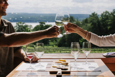 Two wine glasses clinking with the lake in the background.